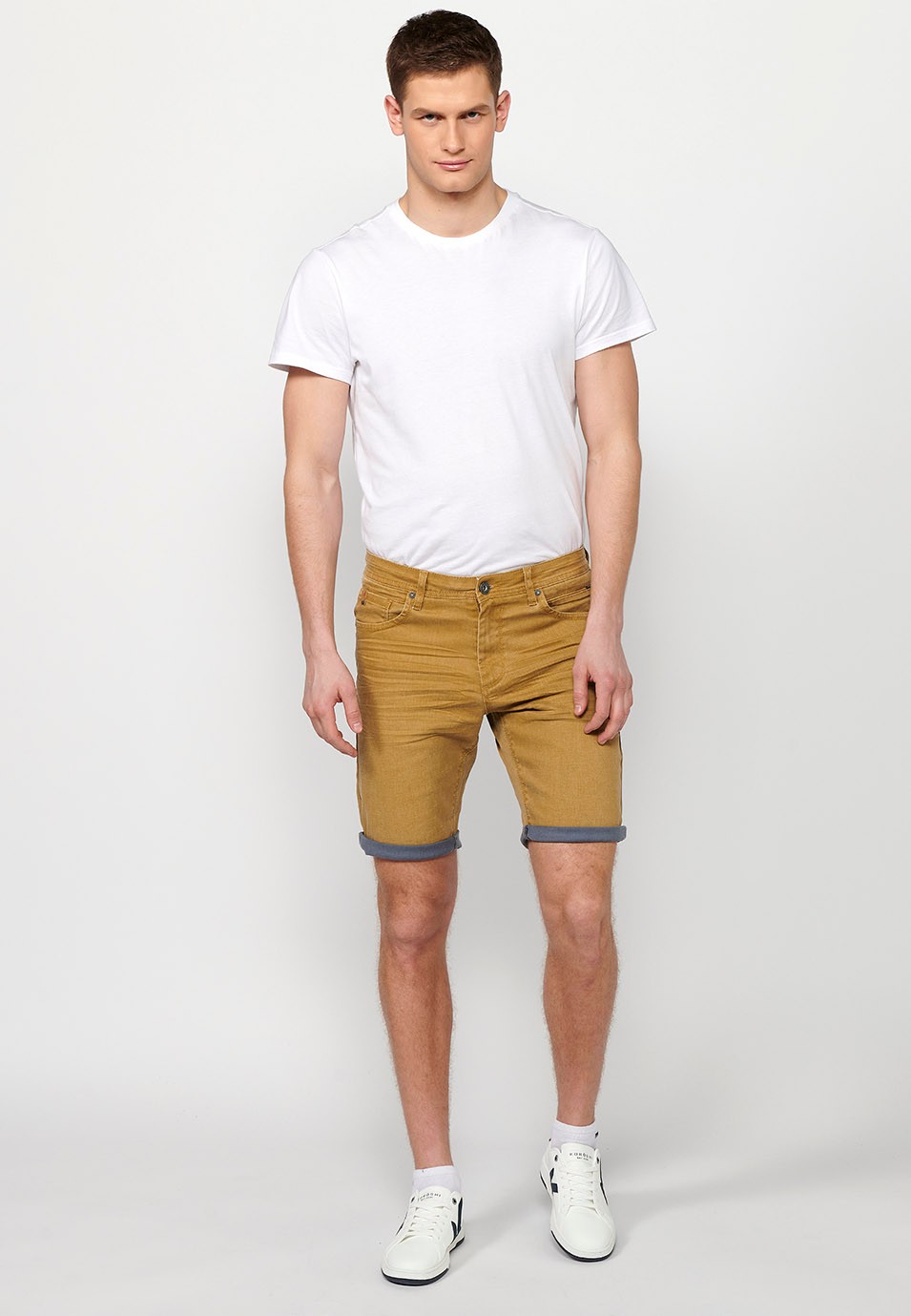 Pantalón corto Bermuda Vaquera con acabado en vuelta de Cierre delantero con cremallera y botón con Cinco bolsillos, uno cerillero de Color Ocre para Hombre