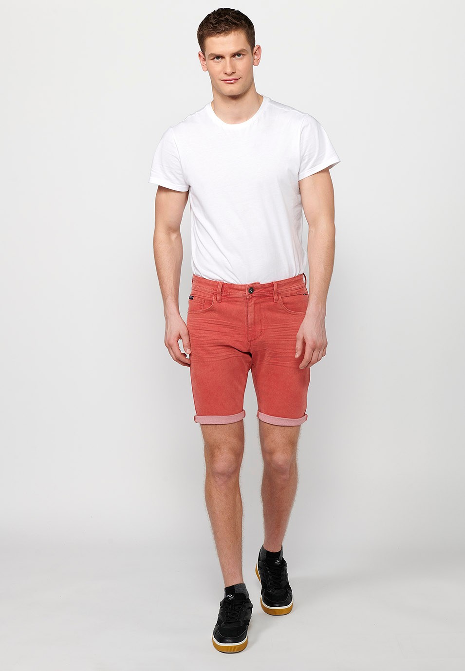 Short à finitions retroussées avec fermeture zippée et boutonnée sur le devant et cinq poches dont une avec poche assortie, en Rouge pour Homme