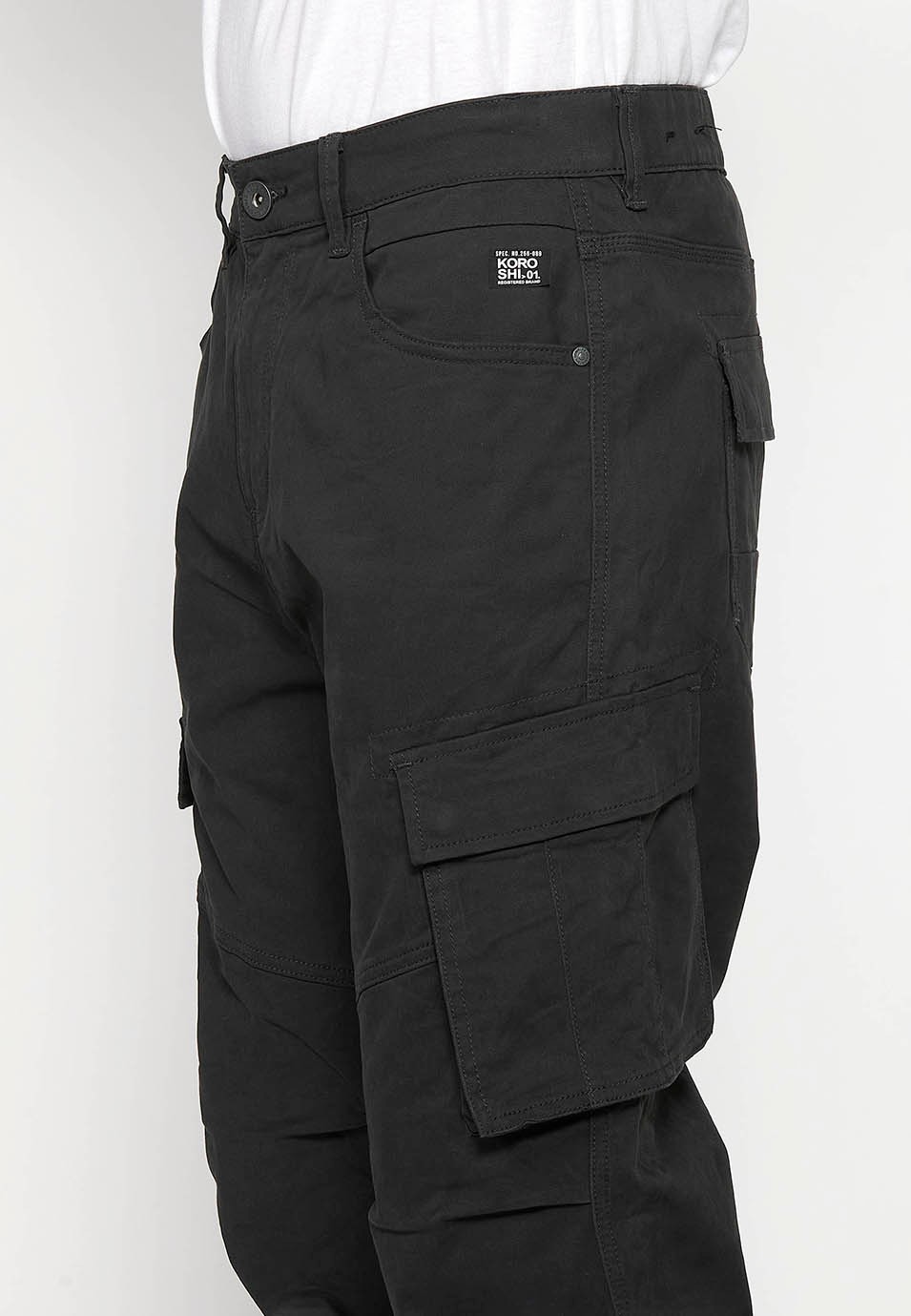 Pantalons llarg càrrec amb Tancament davanter amb cremallera i botó amb Butxaques laterals amb solapa de Color Negre per a Home