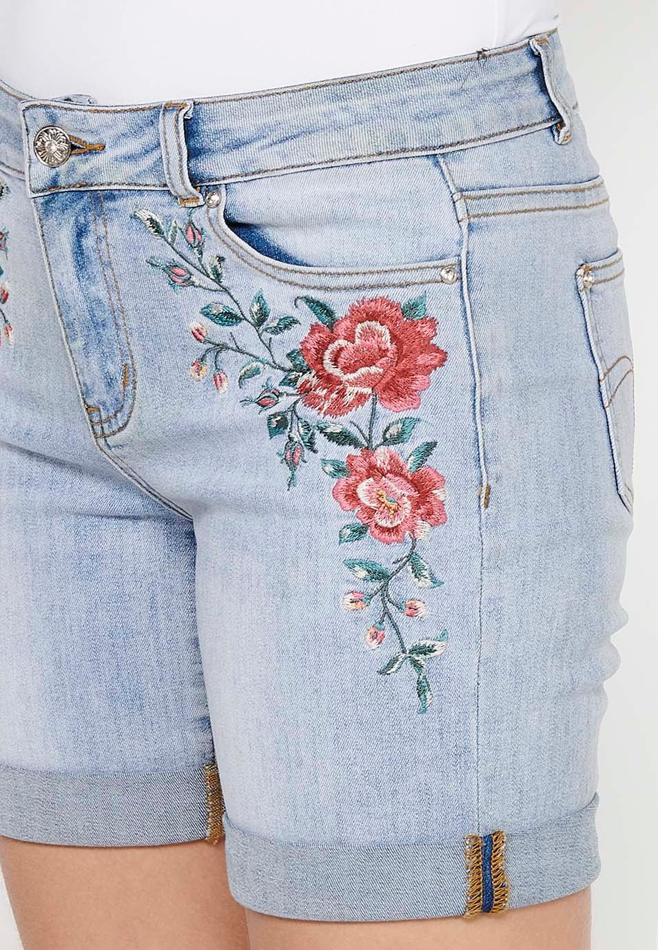 Pantalón corto short denim con cierre delantero con cremallera y botón y detalles bordados florales delanteros con cinco bolsillos, uno cerillero de color azul para mujer | Moda Actual 5