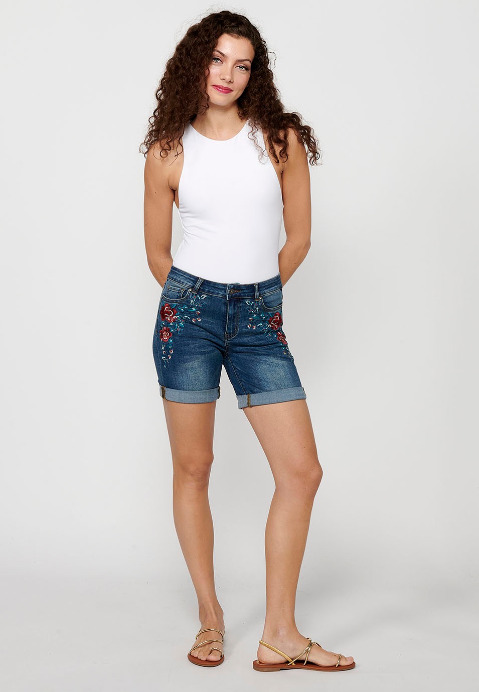 Pantalón corto short denim con cierre delantero con cremallera y botón y detalles bordados florales delanteros con cinco bolsillos, uno cerillero de color azul oscuro para mujer | Moda Actual