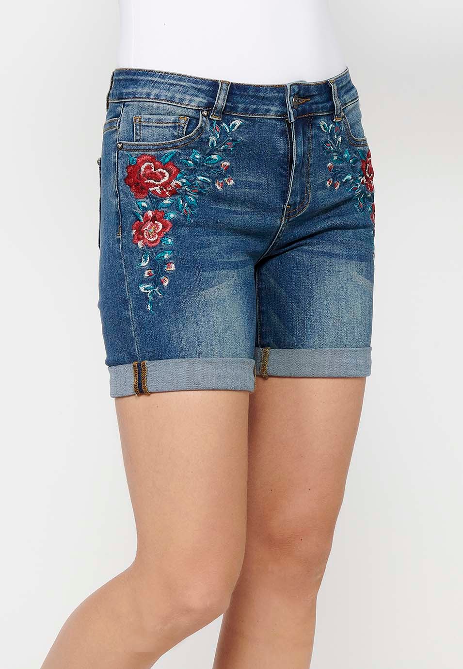 Pantalón corto short denim con cierre delantero con cremallera y botón y detalles bordados florales delanteros con cinco bolsillos, uno cerillero de color azul oscuro para mujer | Moda Actual 4