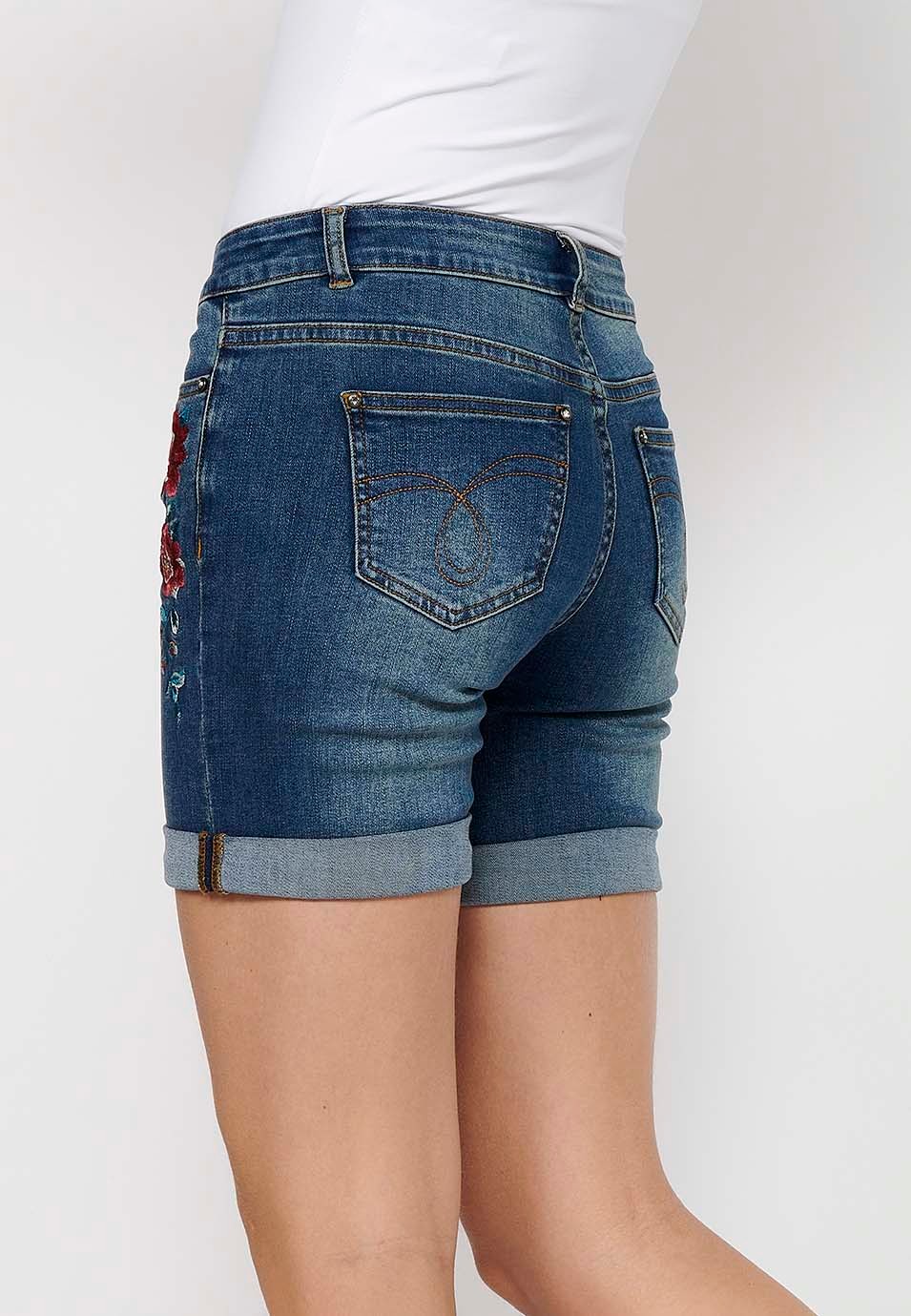 Pantalón corto short denim con cierre delantero con cremallera y botón y detalles bordados florales delanteros con cinco bolsillos, uno cerillero de color azul oscuro para mujer | Moda Actual 7