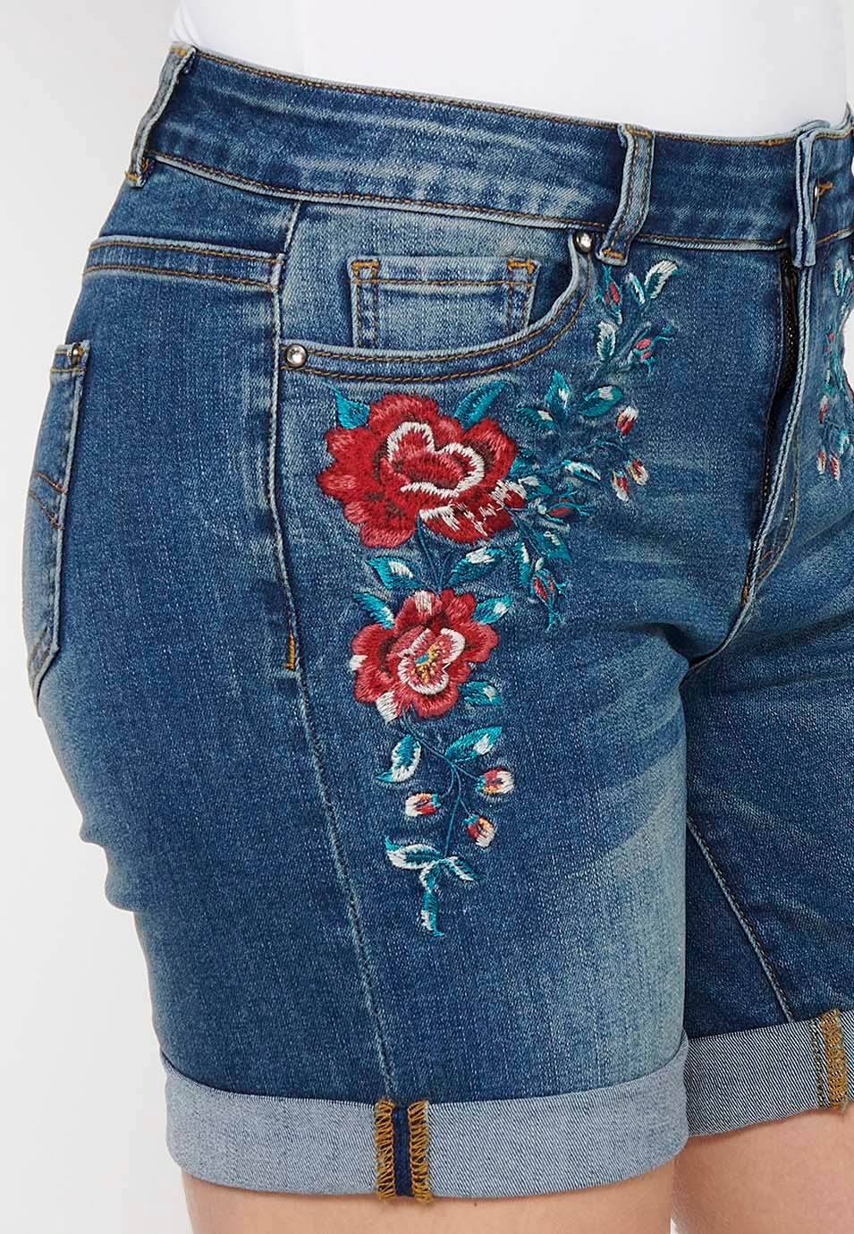 Pantalón corto short denim con cierre delantero con cremallera y botón y detalles bordados florales delanteros con cinco bolsillos, uno cerillero de color azul oscuro para mujer | Moda Actual 9