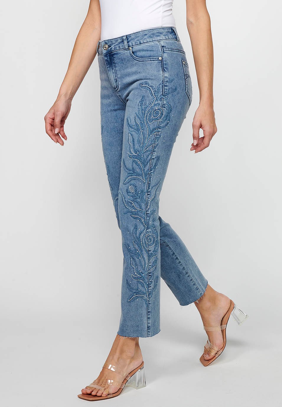 Long flared denim pants with front zipper closure and light blue floral embroidered details for women 3
