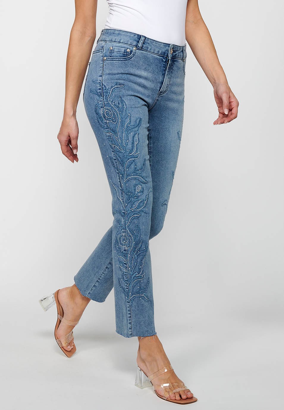 Long flared denim pants with front zipper closure and light blue floral embroidered details for women 1