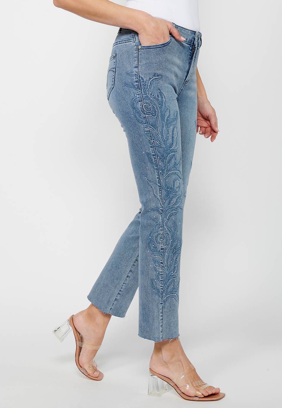 Long flared denim pants with front zipper closure and light blue floral embroidered details for women 8