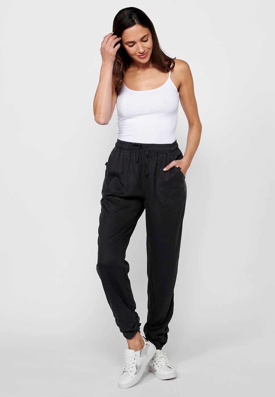 Pantalón largo jogger con acabado rizado y cintura engomada con cuatro bolsillos, dos traseros con solapa de color negro para mujer | Moda Actual