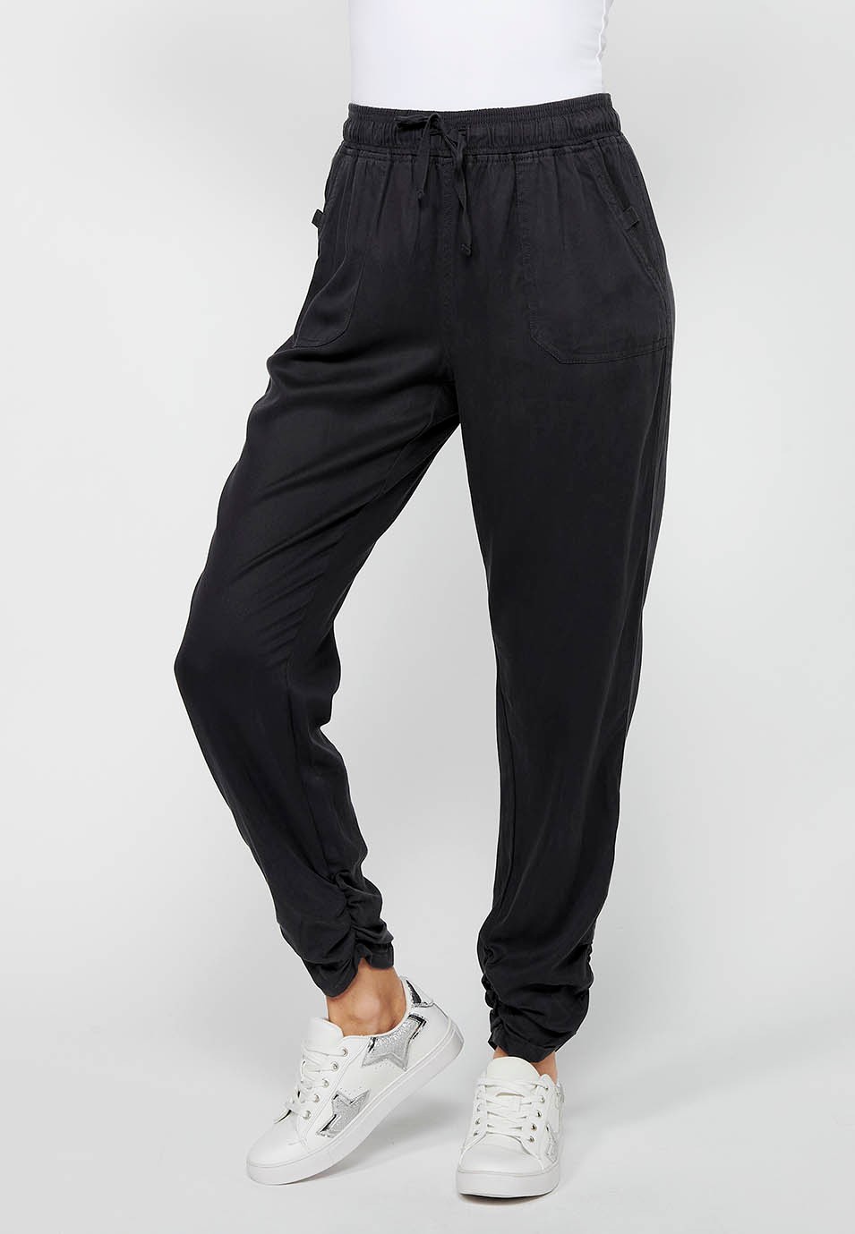 Pantalón largo jogger con acabado rizado y cintura engomada con cuatro bolsillos, dos traseros con solapa de color negro para mujer | Moda Actual 2
