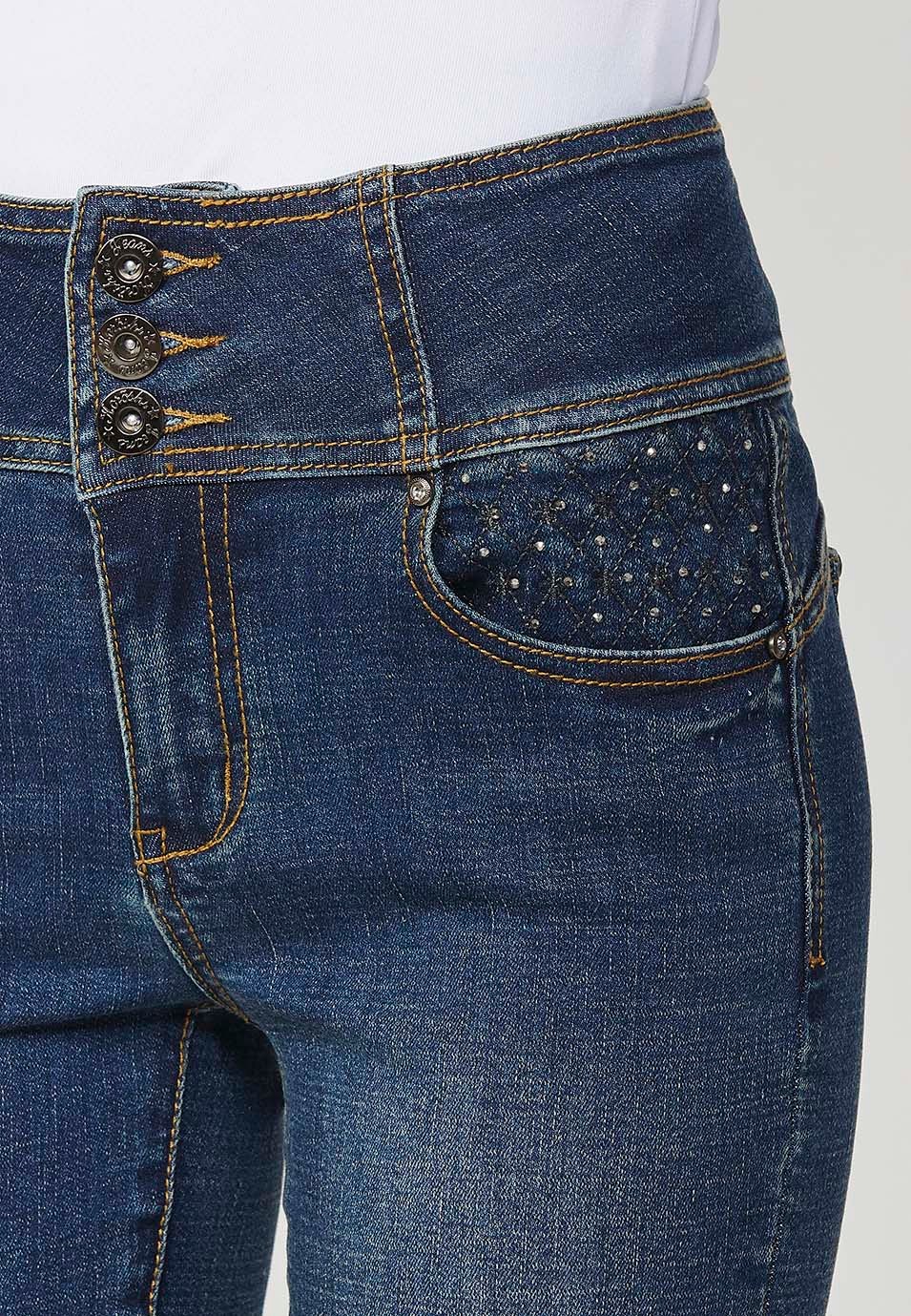 Pantalón denim push up cinco bolsillos con cintura fajín con bordado y aplicaciones metalicas en bolsillos para mujer en color azul oscuro