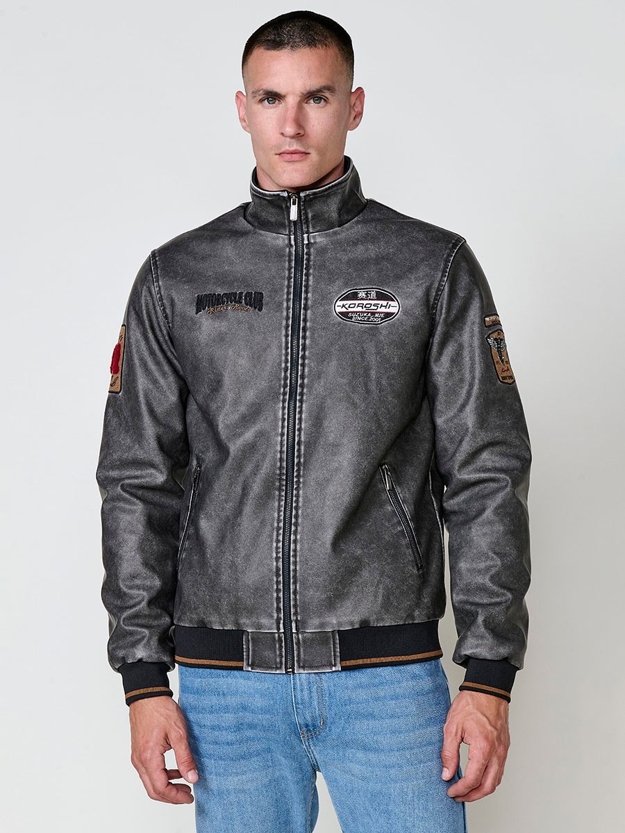 Cazadora gris de hombre con cuello alto, acabados en rib, cremallera, bolsillos y detalle de letras en la espalda. Tejido 100% poliéster.
