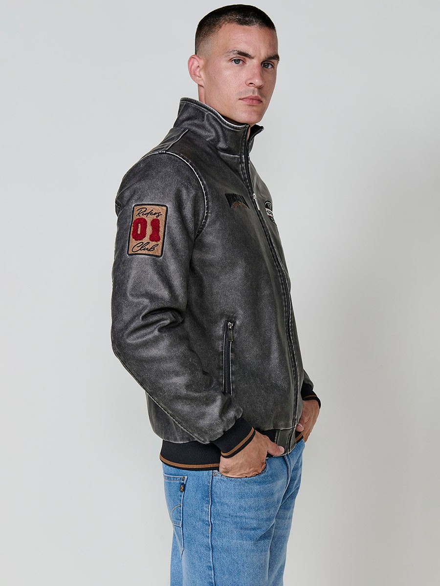 Cazadora gris de hombre con cuello alto, acabados en rib, cremallera, bolsillos y detalle de letras en la espalda. Tejido 100% poliéster.