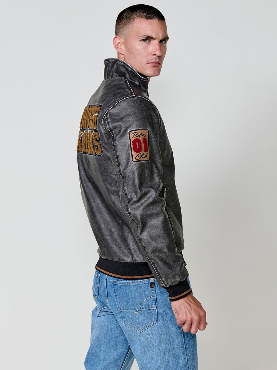 Cazadora gris de hombre con cuello alto, acabados en rib, cremallera, bolsillos y detalle de letras en la espalda. Tejido 100% poliéster.