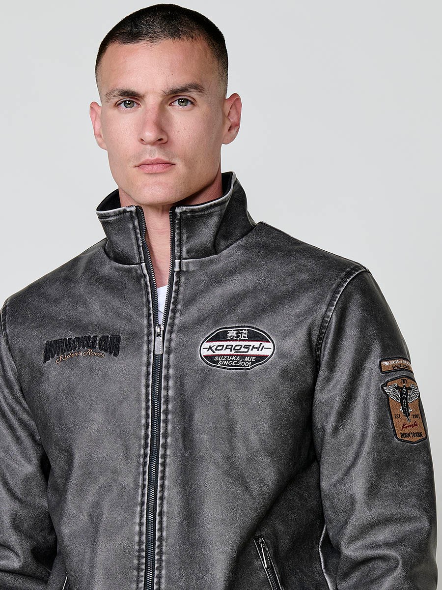 Cazadora gris de hombre con cuello alto, acabados en rib, cremallera, bolsillos y detalle de letras en la espalda. Tejido 100% poliéster.
