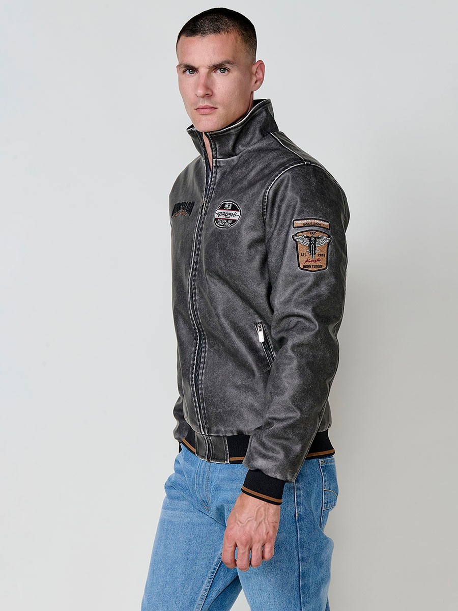 Cazadora gris de hombre con cuello alto, acabados en rib, cremallera, bolsillos y detalle de letras en la espalda. Tejido 100% poliéster.