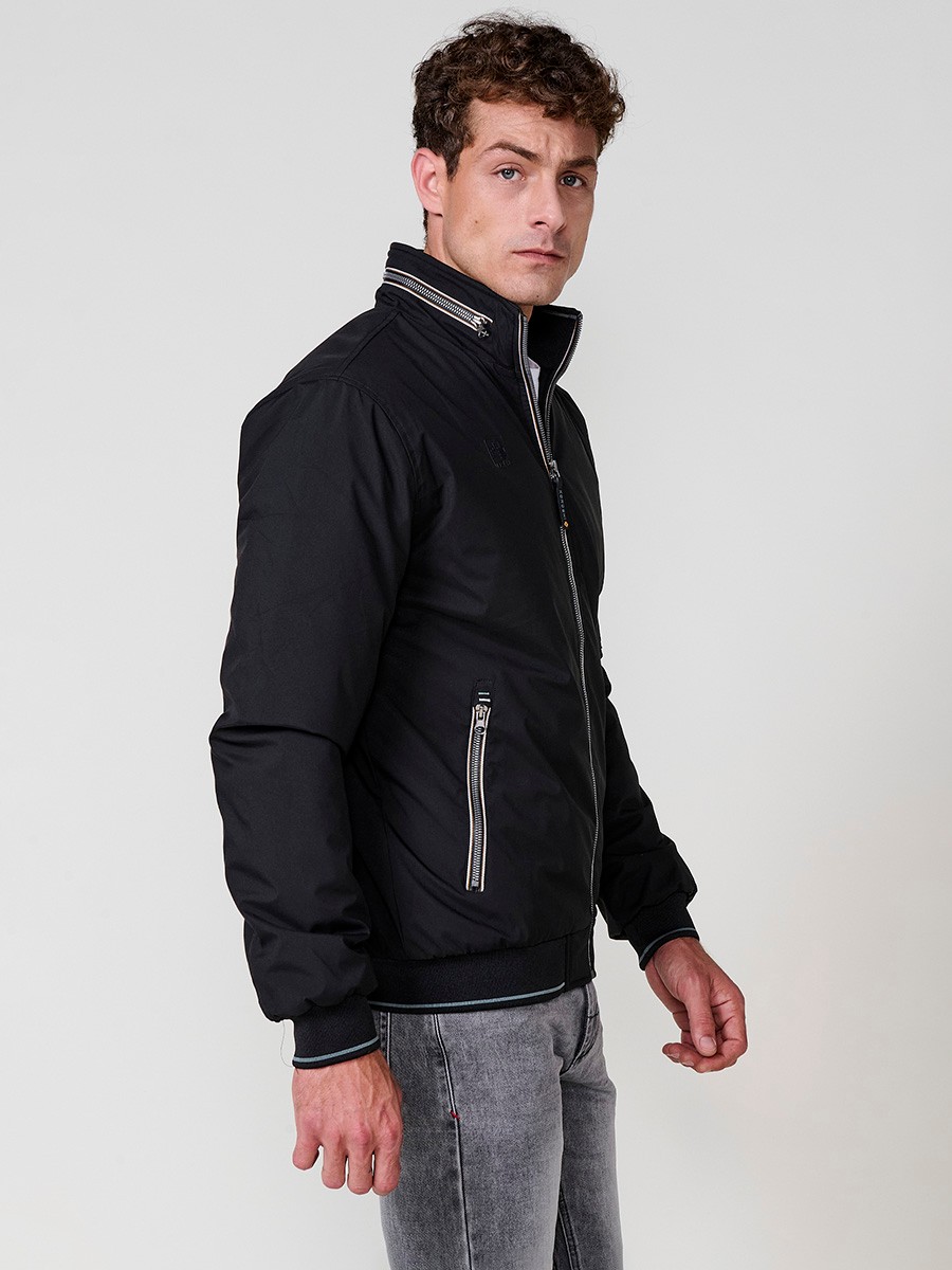 Cazadora de hombre en color negro con cuello alto y cierre delantero con cremallera. Confeccionada en 100% poliéster, cómoda y versátil.