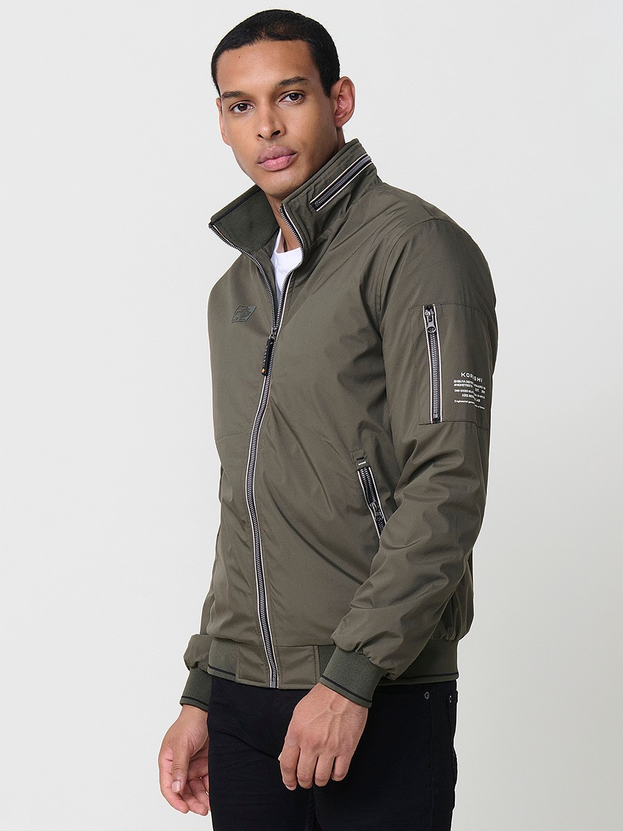 Cazadora de hombre en color kaki con cuello alto y cierre delantero con cremallera. Confeccionada en 100% poliéster, ligera, práctica y versátil.