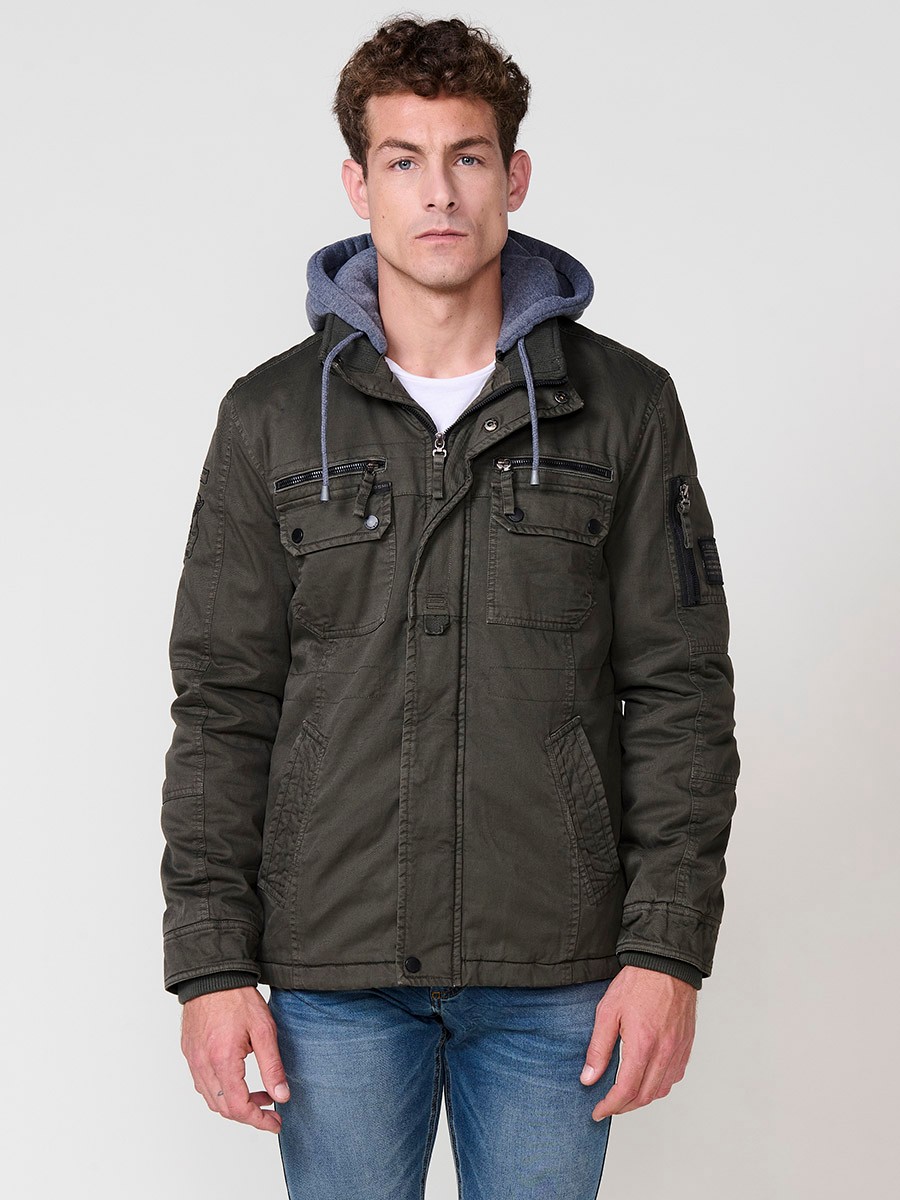 Cazadora oliva de hombre con capucha, bolsillos y cierre delantero de cremallera. Confeccionada en 100% algodón, cómoda y transpirable.
