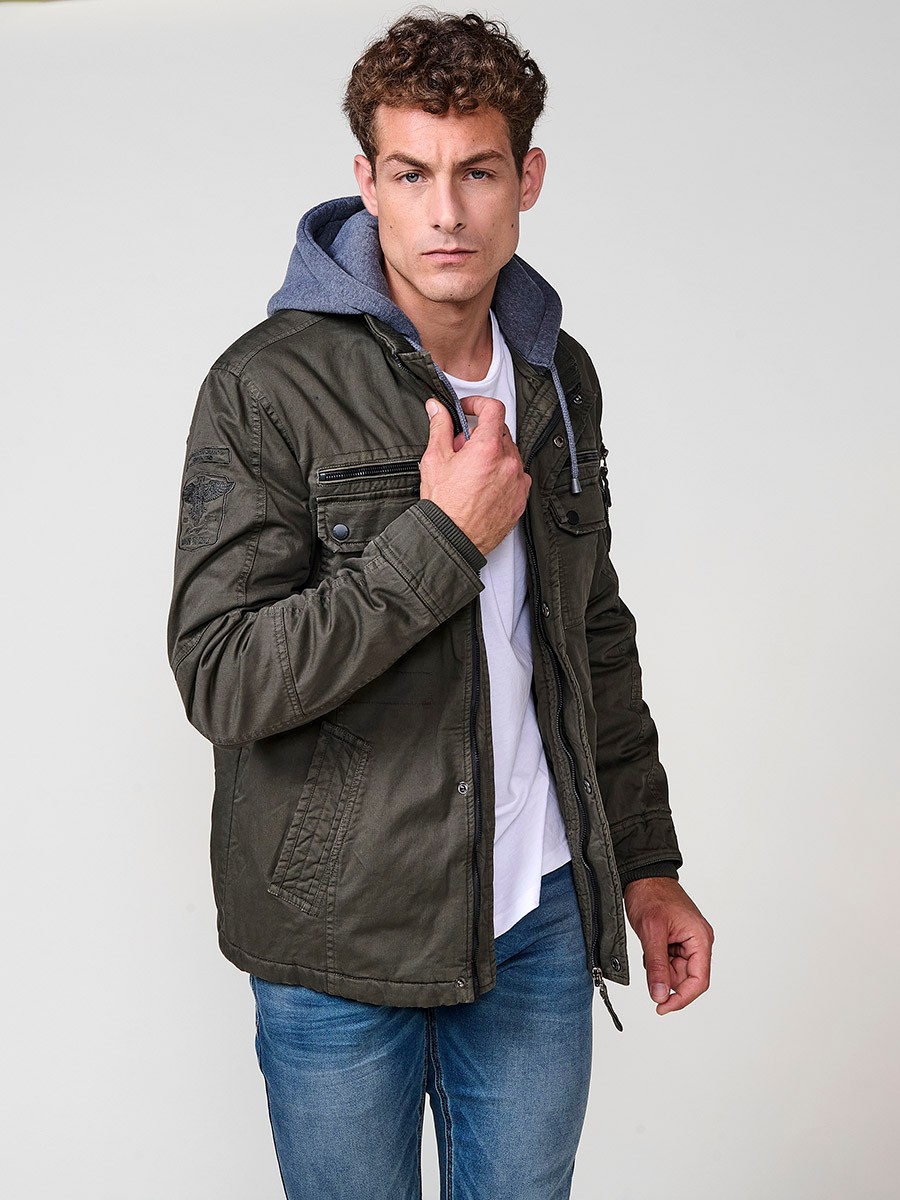 Cazadora oliva de hombre con capucha, bolsillos y cierre delantero de cremallera. Confeccionada en 100% algodón, cómoda y transpirable.