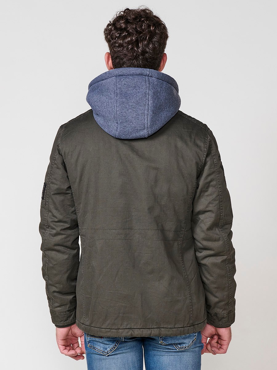 Cazadora oliva de hombre con capucha, bolsillos y cierre delantero de cremallera. Confeccionada en 100% algodón, cómoda y transpirable.