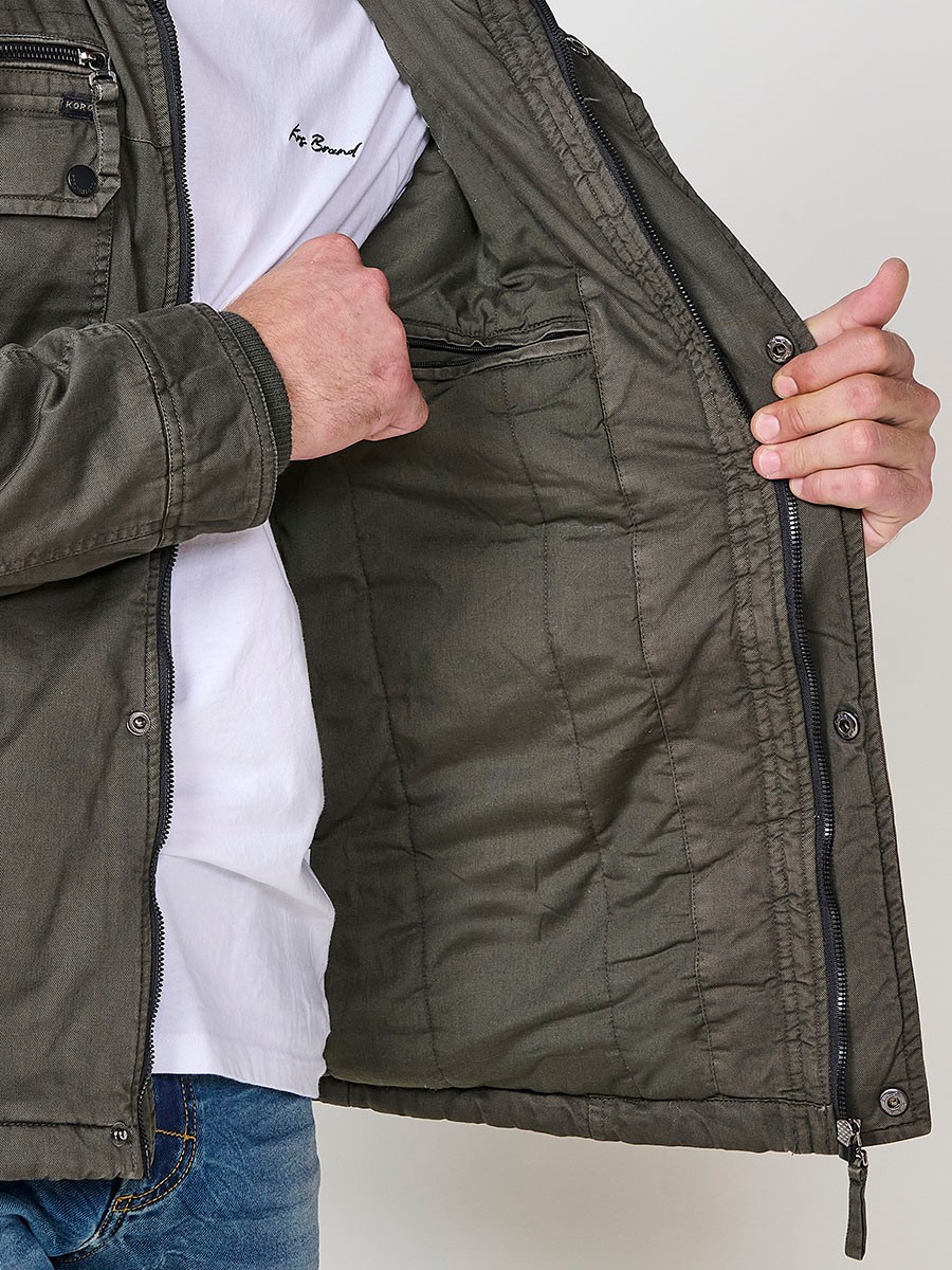 Cazadora oliva de hombre con capucha, bolsillos y cierre delantero de cremallera. Confeccionada en 100% algodón, cómoda y transpirable.