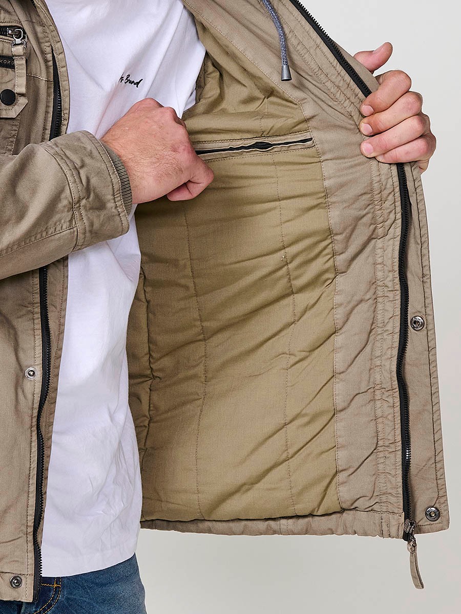 Cazadora visón de hombre con capucha, bolsillos y cierre delantero de cremallera. Confeccionada en 100% algodón, cómoda y transpirable.