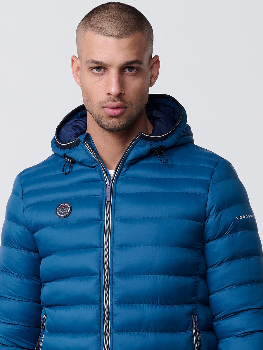 Gesteppte blaue Herrenjacke mit hohem Kragen, Kapuze, Reißverschluss und Taschen. Aus 100 % Polyester, warm und strapazierfähig.