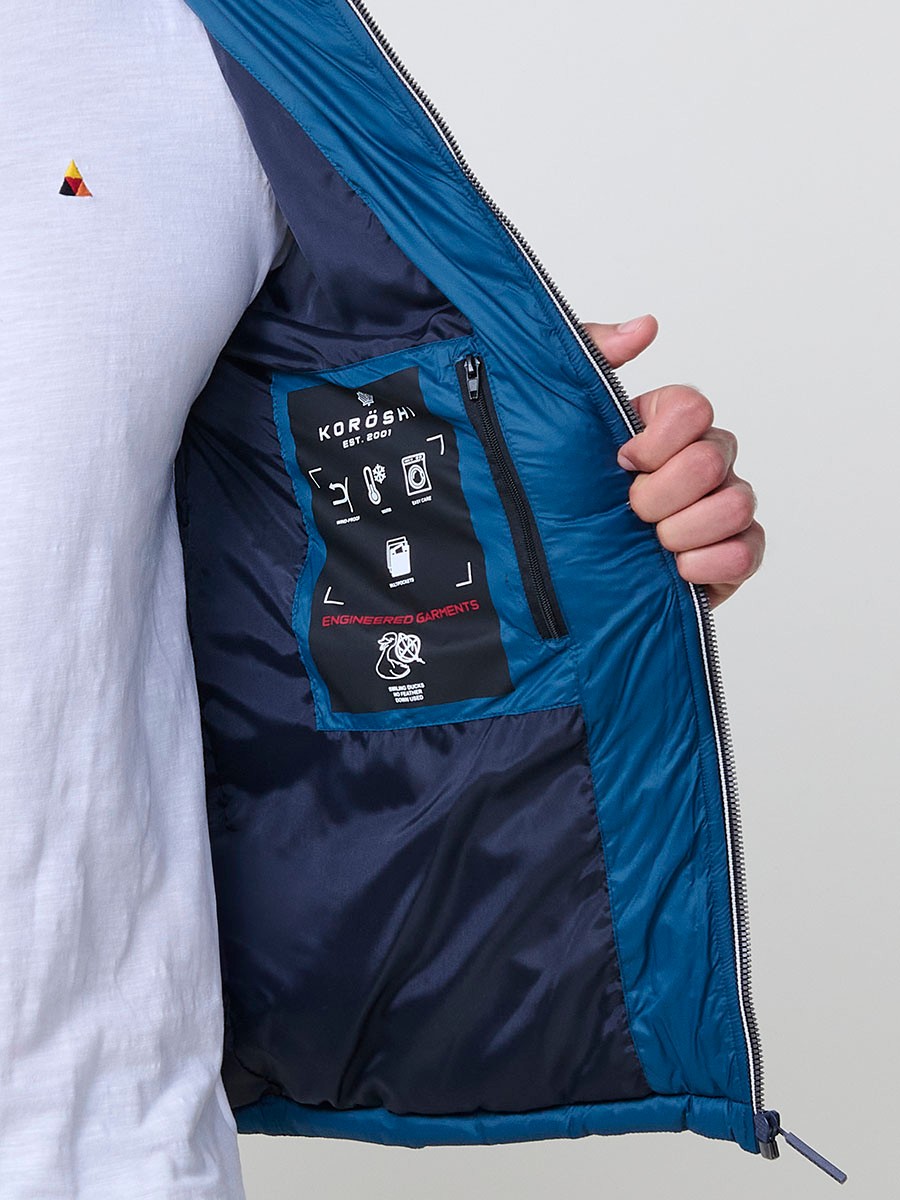 Gesteppte blaue Herrenjacke mit hohem Kragen, Kapuze, Reißverschluss und Taschen. Aus 100 % Polyester, warm und strapazierfähig.