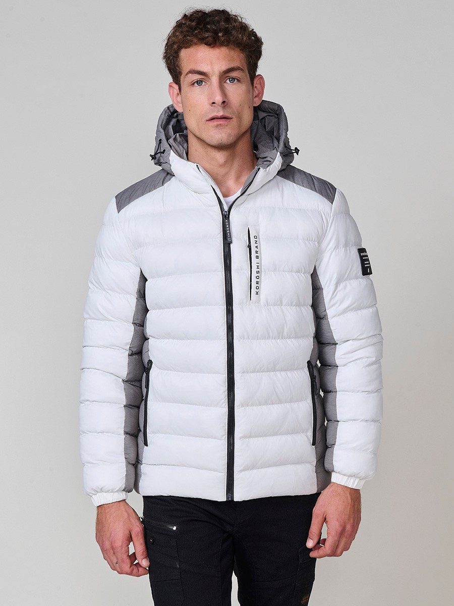 Gesteppte ecrufarbene Herrenjacke mit hohem Kragen, Kapuze, Reißverschluss und Taschen. Aus 100 % Polyester, warm und strapazierfähig.
