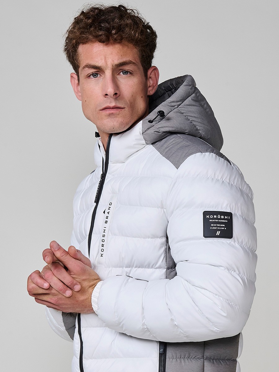 Gesteppte ecrufarbene Herrenjacke mit hohem Kragen, Kapuze, Reißverschluss und Taschen. Aus 100 % Polyester, warm und strapazierfähig.