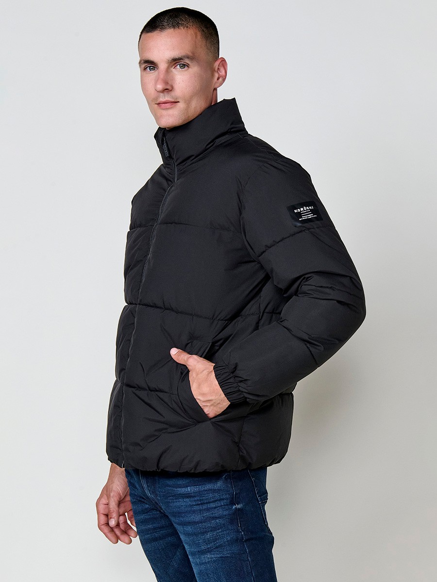 Gesteppte schwarze Herrenjacke mit hohem Kragen, Reißverschluss und Taschen. Aus 100 % Polyester, warm und strapazierfähig.