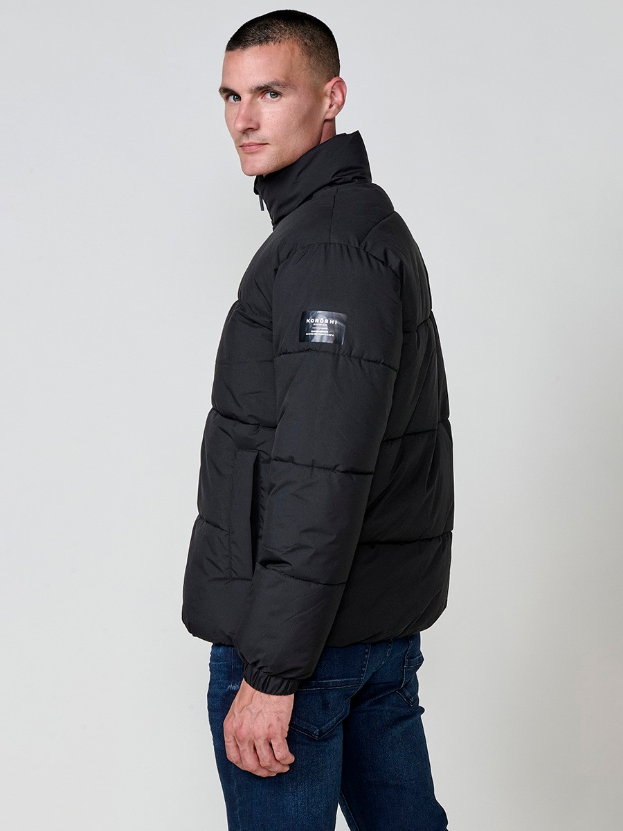 Gesteppte schwarze Herrenjacke mit hohem Kragen, Reißverschluss und Taschen. Aus 100 % Polyester, warm und strapazierfähig.