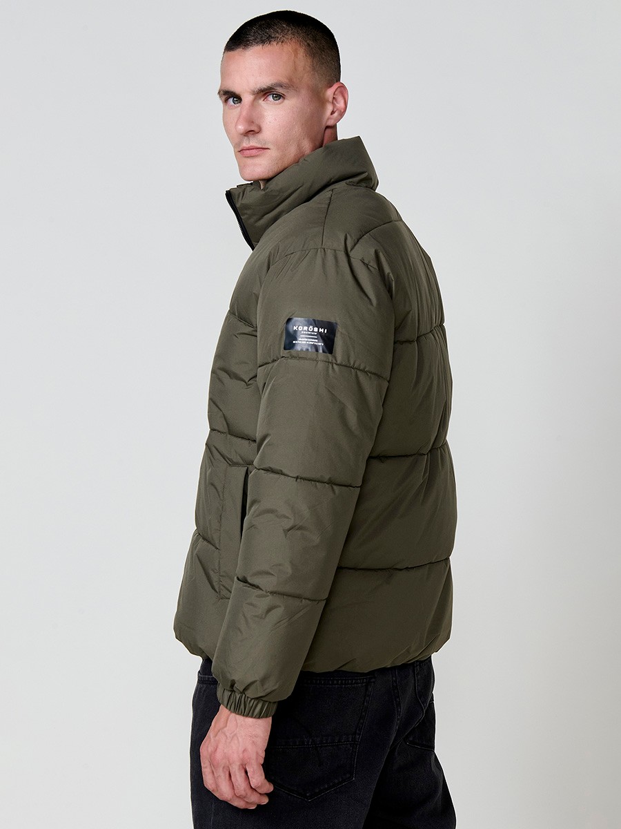 Gesteppte khakifarbene Herrenjacke mit hohem Kragen, Reißverschluss und Taschen. Aus 100 % Polyester, warm und strapazierfähig.