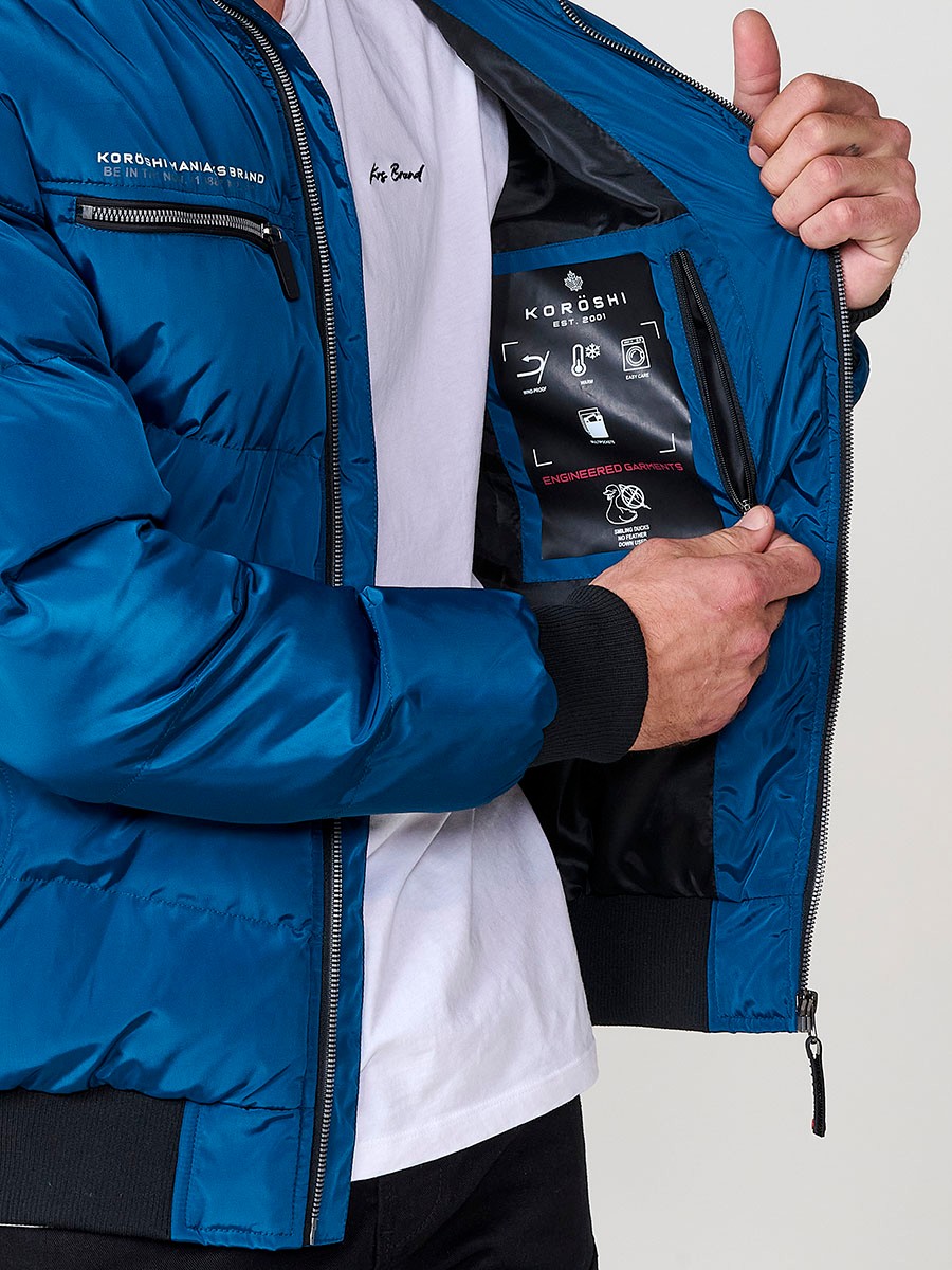 Gesteppte blaue Herrenjacke mit hohem Kragen, Kapuze, Reißverschluss und Taschen. Aus 100 % Polyester, warm und strapazierfähig.