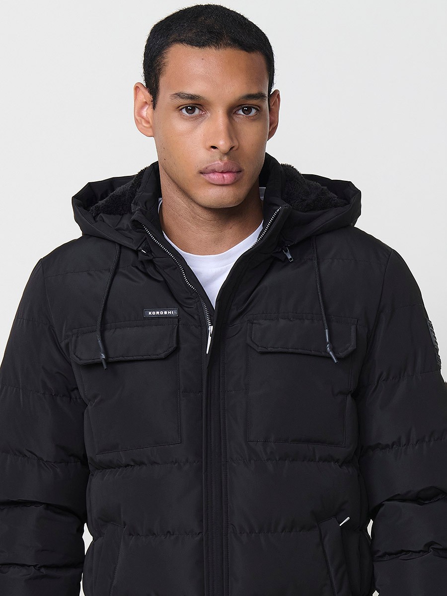 Gesteppte schwarze Herrenjacke mit hohem Kragen, Kapuze, Reißverschluss und Taschen. Aus 100 % Polyester, warm und strapazierfähig.