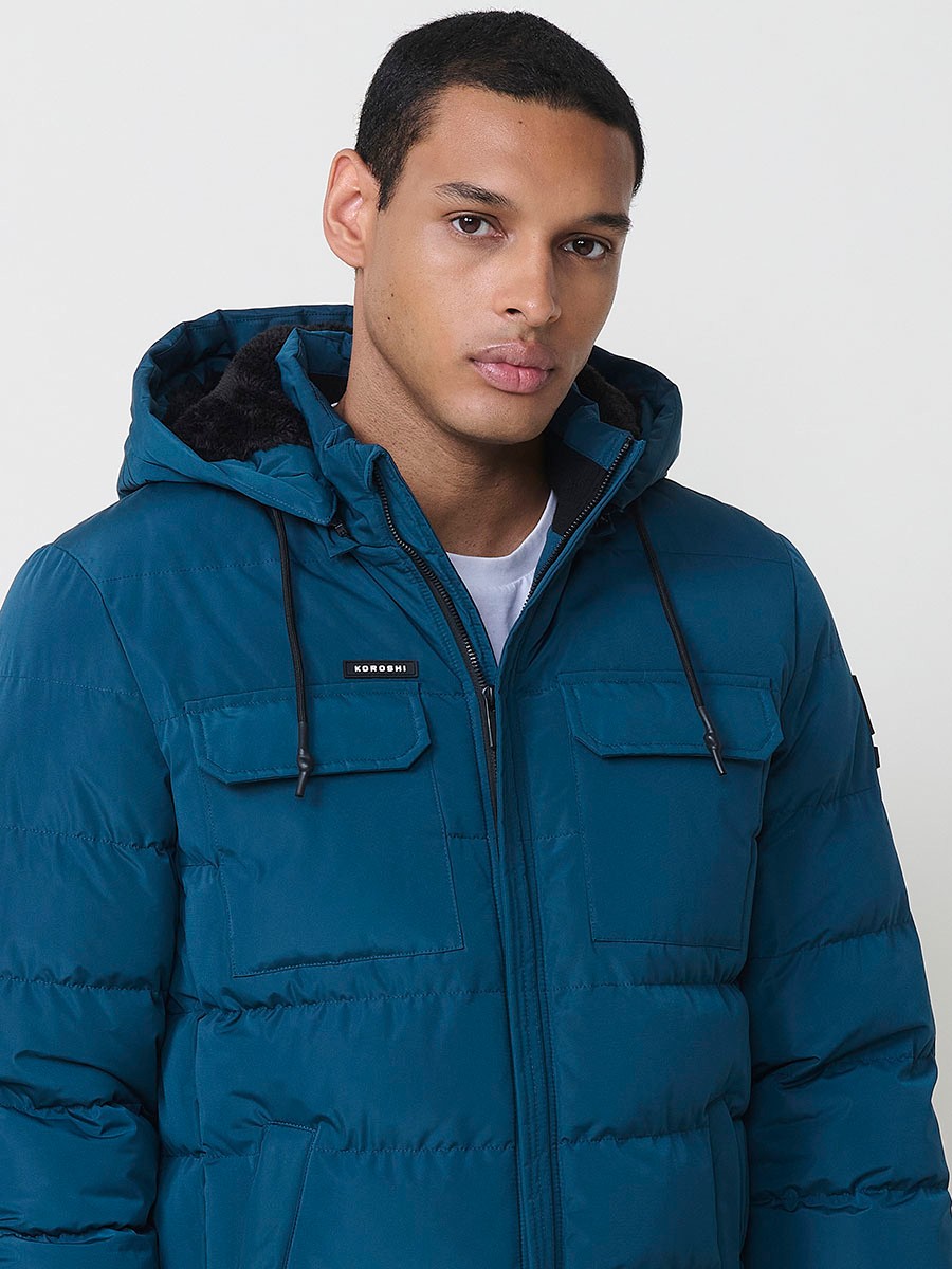 Gesteppte blaue Herrenjacke mit hohem Kragen, Kapuze, Reißverschluss und Taschen. Aus 100 % Polyester, warm und strapazierfähig.