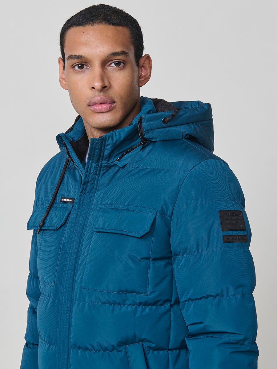 Gesteppte blaue Herrenjacke mit hohem Kragen, Kapuze, Reißverschluss und Taschen. Aus 100 % Polyester, warm und strapazierfähig.