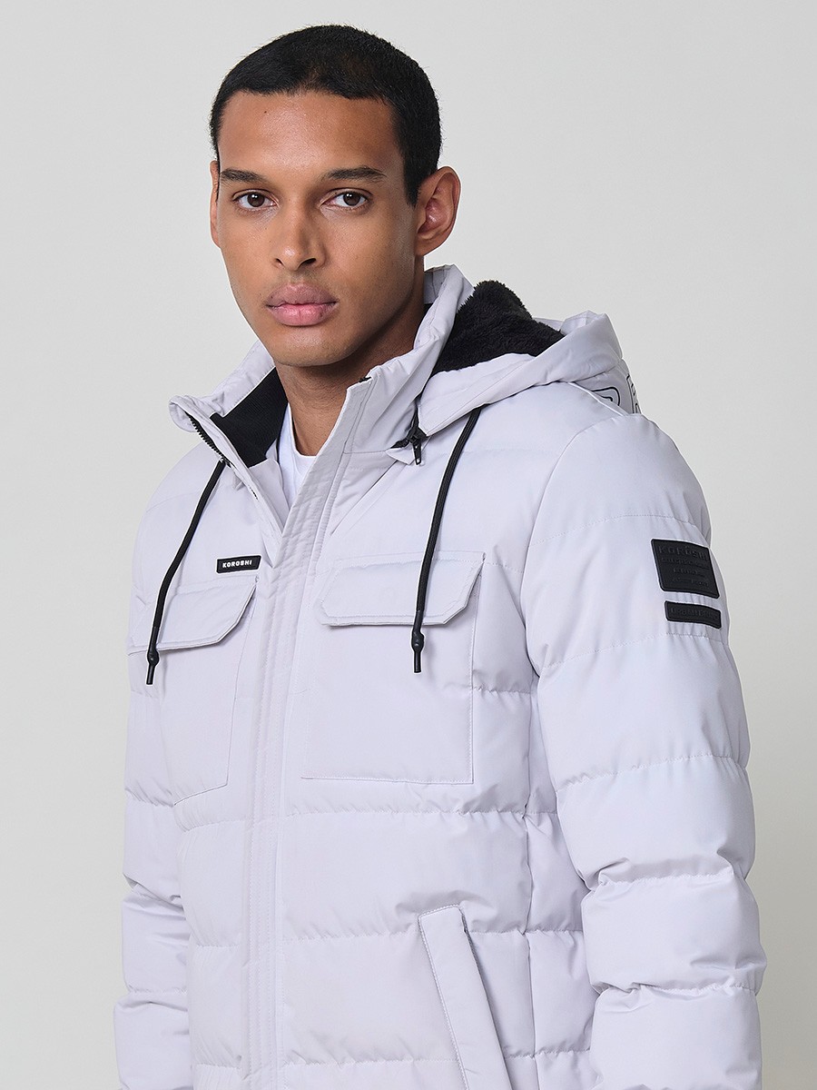 Gesteppte perlgraue Herrenjacke mit hohem Kragen, Kapuze, Reißverschluss und Taschen. Aus 100 % Polyester, warm und strapazierfähig.