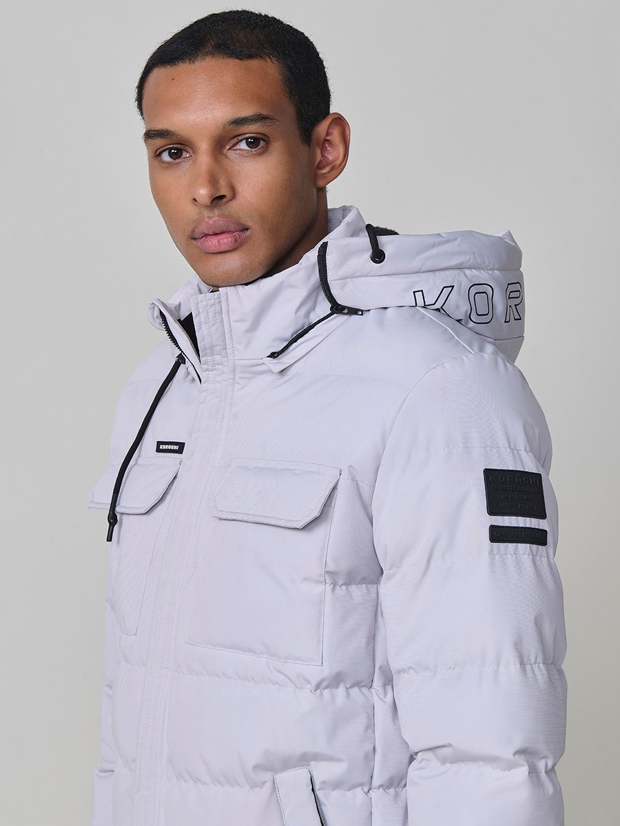 Gesteppte perlgraue Herrenjacke mit hohem Kragen, Kapuze, Reißverschluss und Taschen. Aus 100 % Polyester, warm und strapazierfähig.