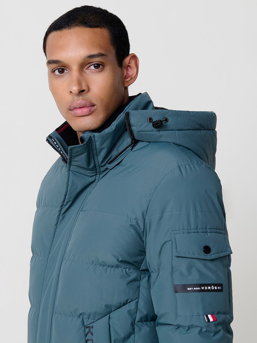 Gesteppte blaue Herrenjacke mit hohem Kragen, Kapuze, Reißverschluss und Taschen. Aus 100 % Polyester, warm und strapazierfähig.