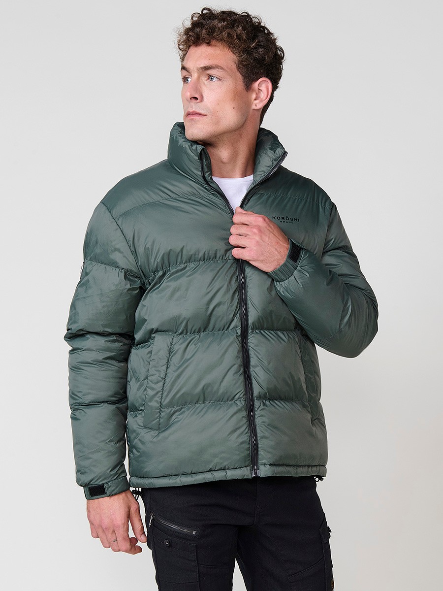Gesteppte grüne Herrenjacke mit hohem Kragen und Frontreißverschluss. Aus 100 % Polyamid, leicht, strapazierfähig und warm.