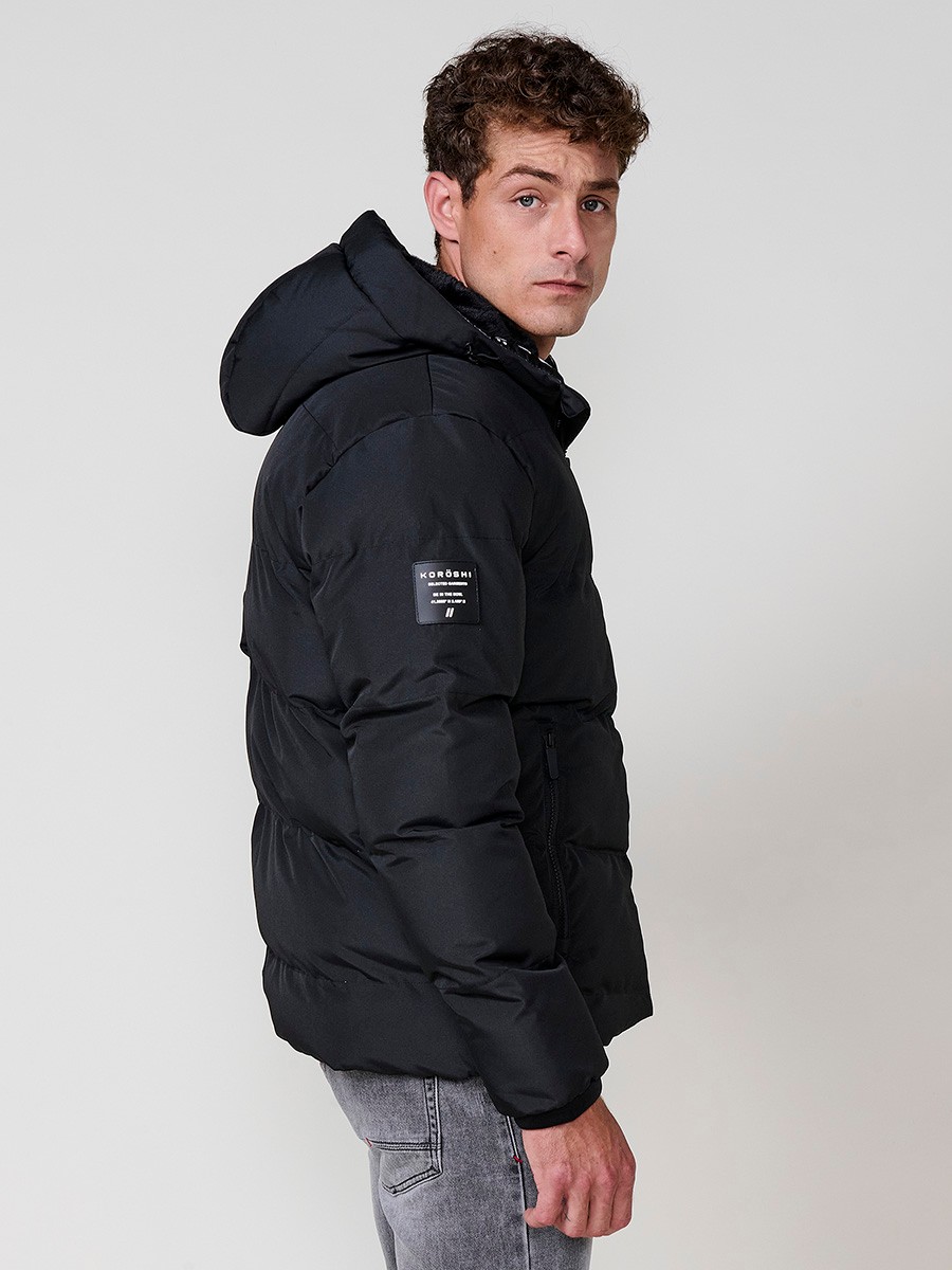 Veste matelassée homme noire avec capuche, col montant, fermeture zippée noire et poches. 100 % polyester, résistante et chaude.
