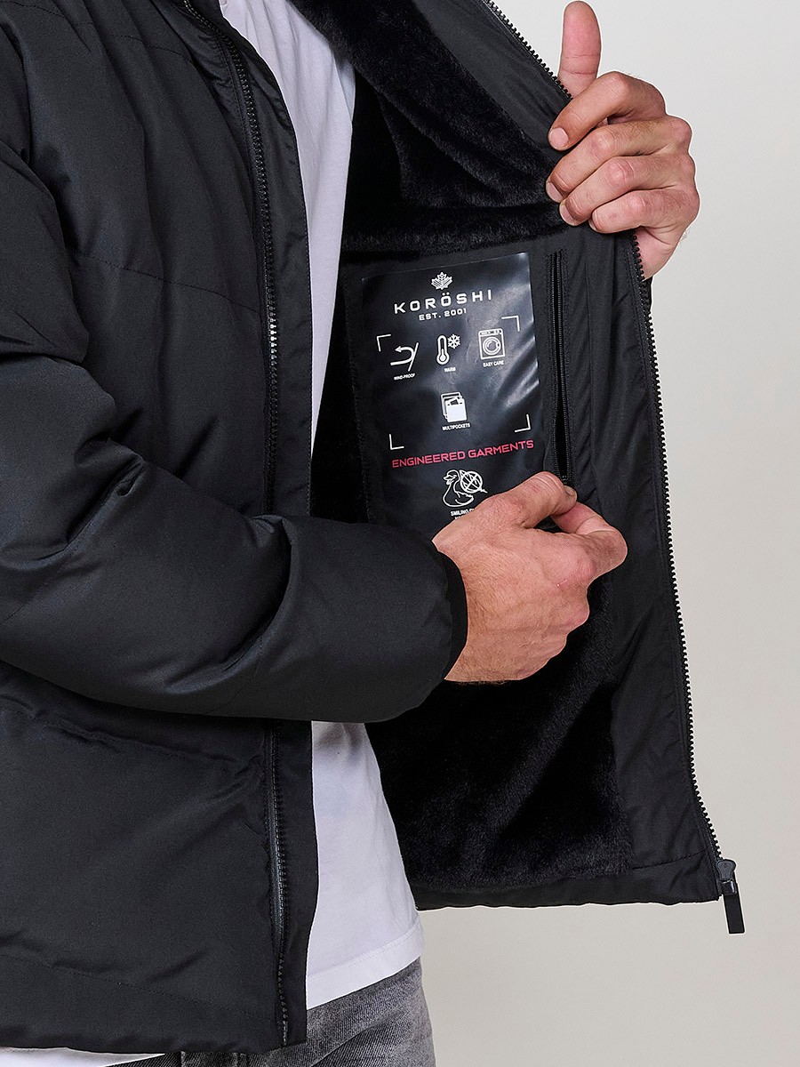 Veste matelassée homme noire avec capuche, col montant, fermeture zippée noire et poches. 100 % polyester, résistante et chaude.