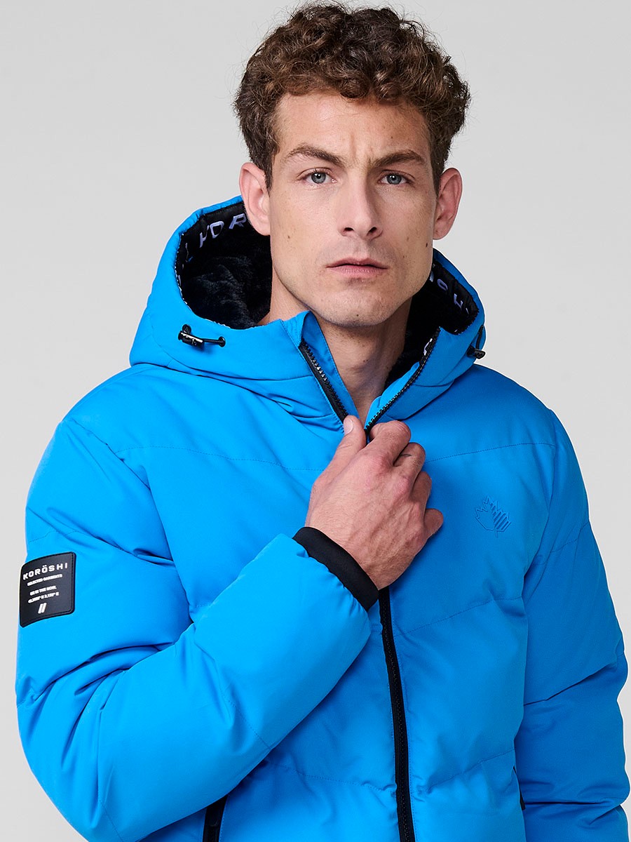 Gesteppte hellblaue Herrenjacke mit hohem Kragen, Kapuze, Reißverschluss und Taschen. Aus 100 % Polyester, warm, strapazierfähig und modern.