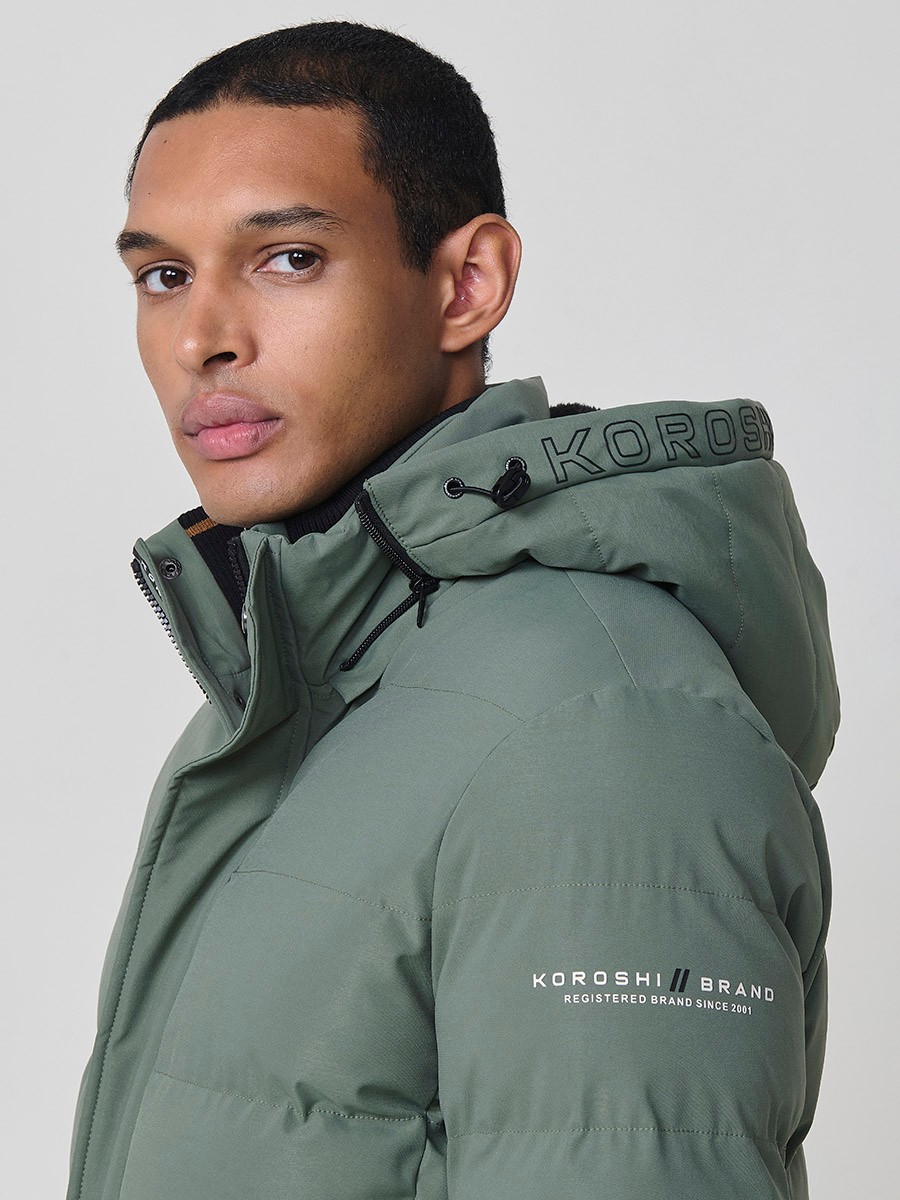 Gesteppte grüne Herrenjacke mit hohem Kragen, Kapuze, Reißverschluss und Taschen. Aus 100 % Polyester, warm, strapazierfähig und leicht.