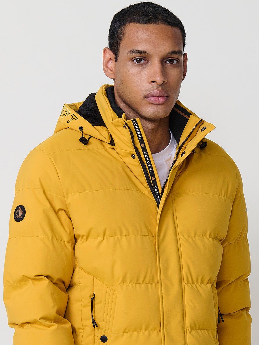 Gesteppte gelbe Herrenjacke mit hohem Kragen, Kapuze, Reißverschluss und Taschen. Aus 100 % Polyester, warm, leicht und strapazierfähig.