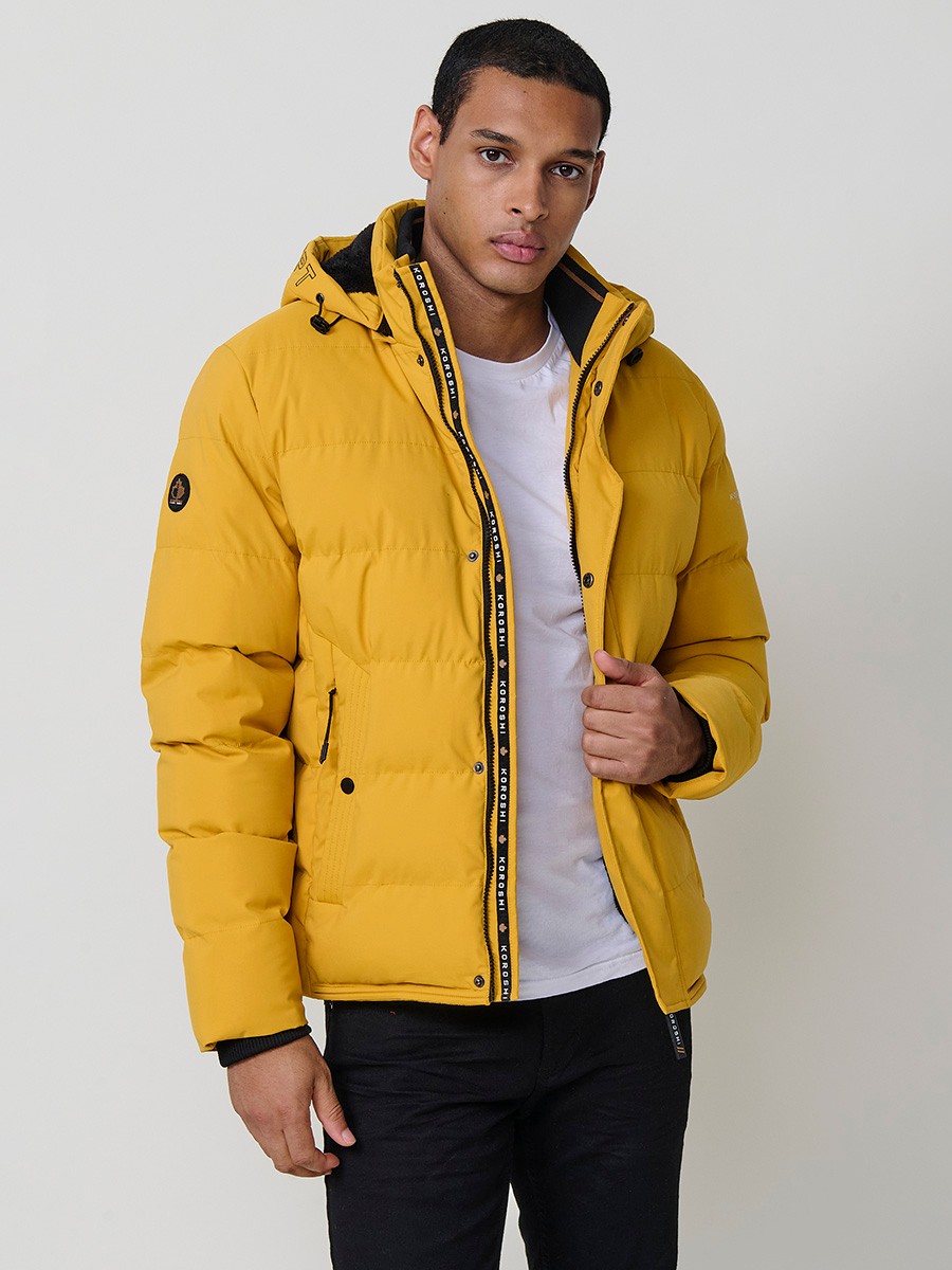 Gesteppte gelbe Herrenjacke mit hohem Kragen, Kapuze, Reißverschluss und Taschen. Aus 100 % Polyester, warm, leicht und strapazierfähig.