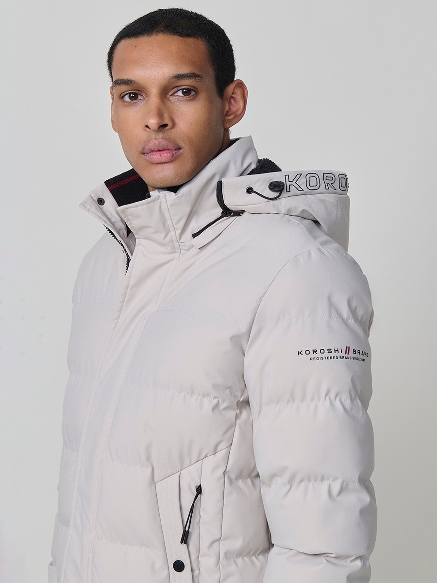 Gesteppte steinfarbene Herrenjacke mit hohem Kragen, Kapuze, Reißverschluss und Taschen. Aus 100 % Polyester, warm, strapazierfähig und leicht.