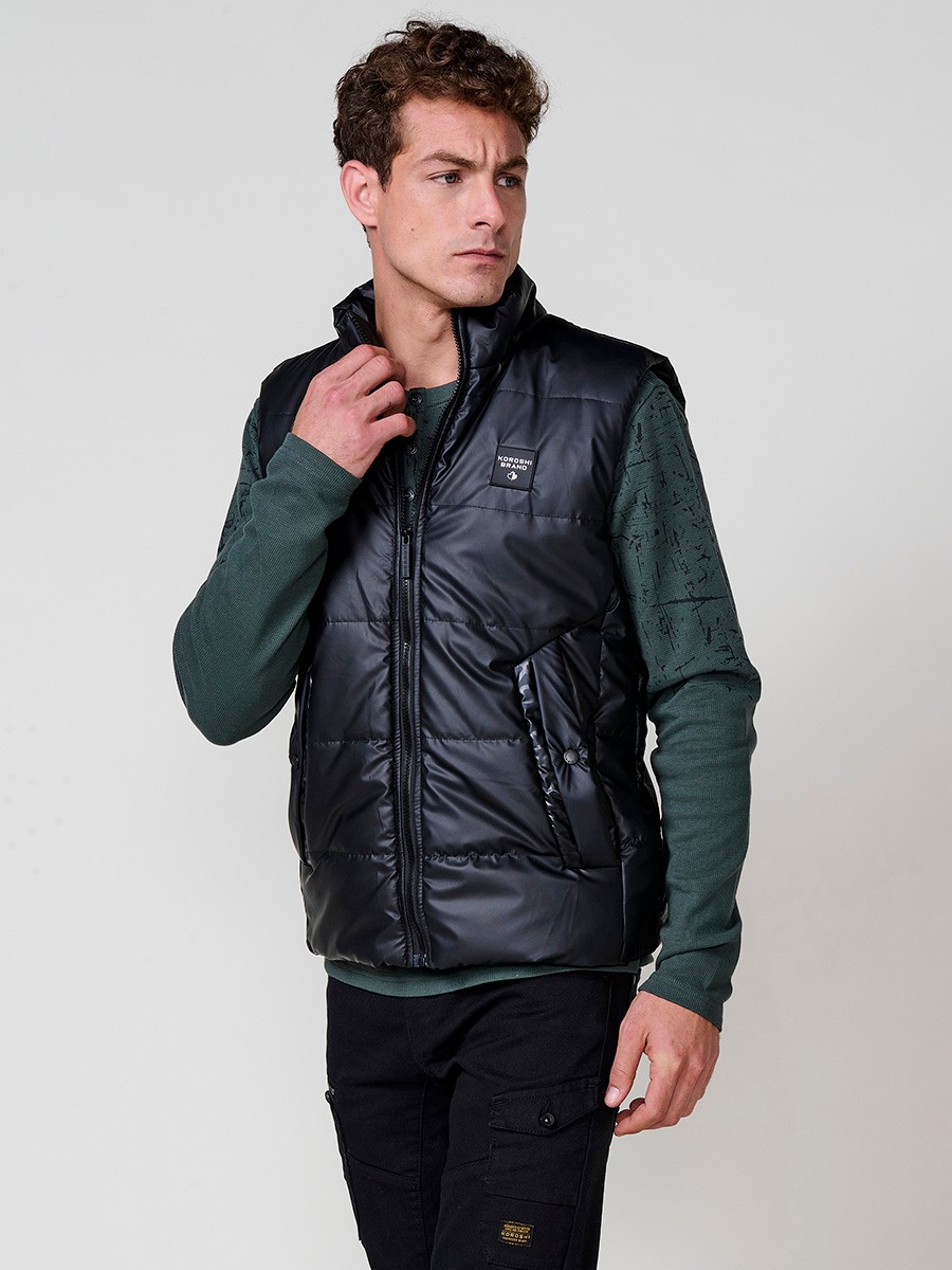 Chaleco acolchado negro de hombre con cuello alto y cierre delantero de cremallera. Confeccionado en 100% poliéster, ligero, resistente y versátil.