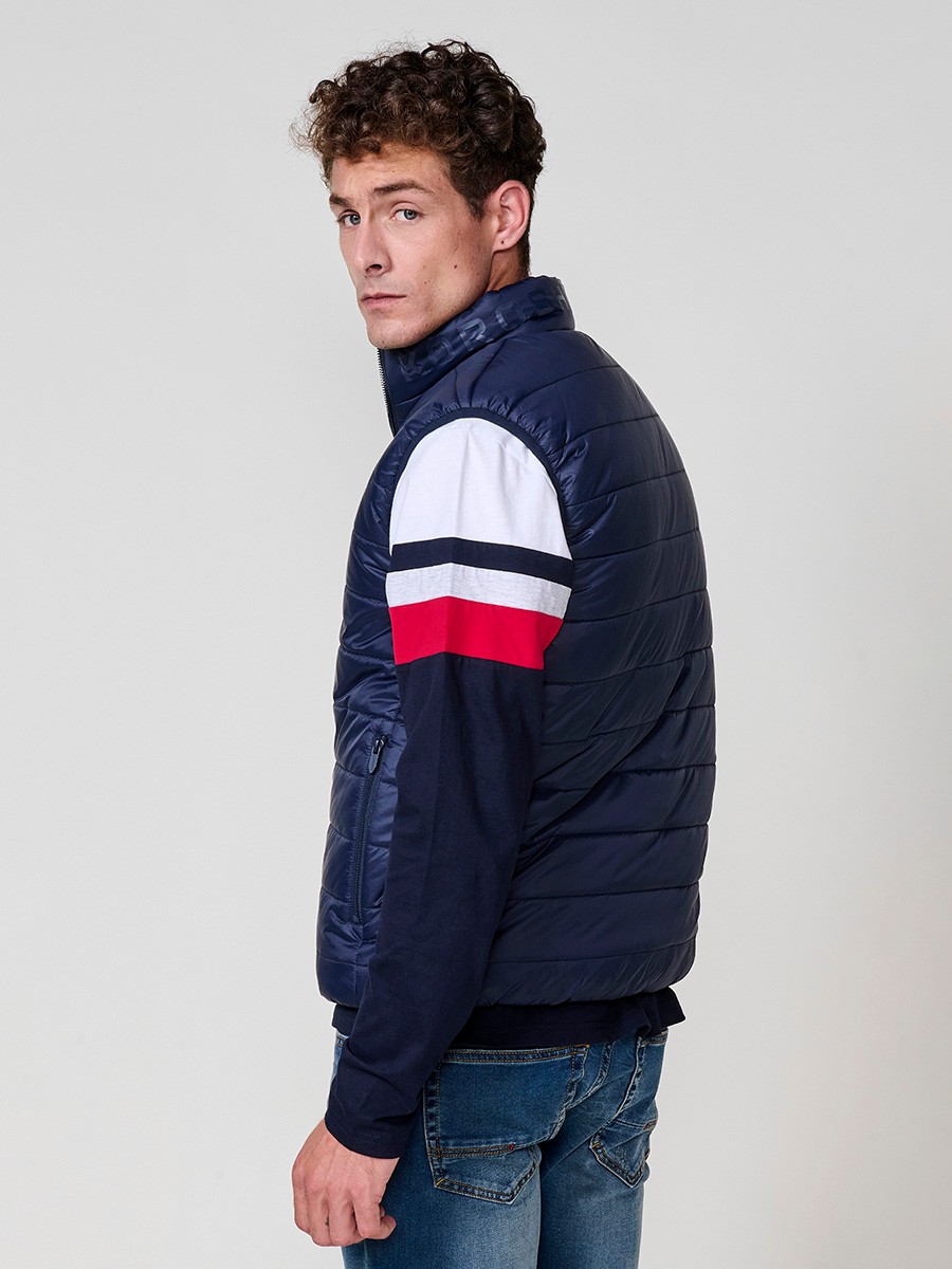 Armilla encoixinada reversible d’home navy amb coll alt i cremallera. Confeccionada en 100 % polièster, pràctica, lleugera i versàtil.